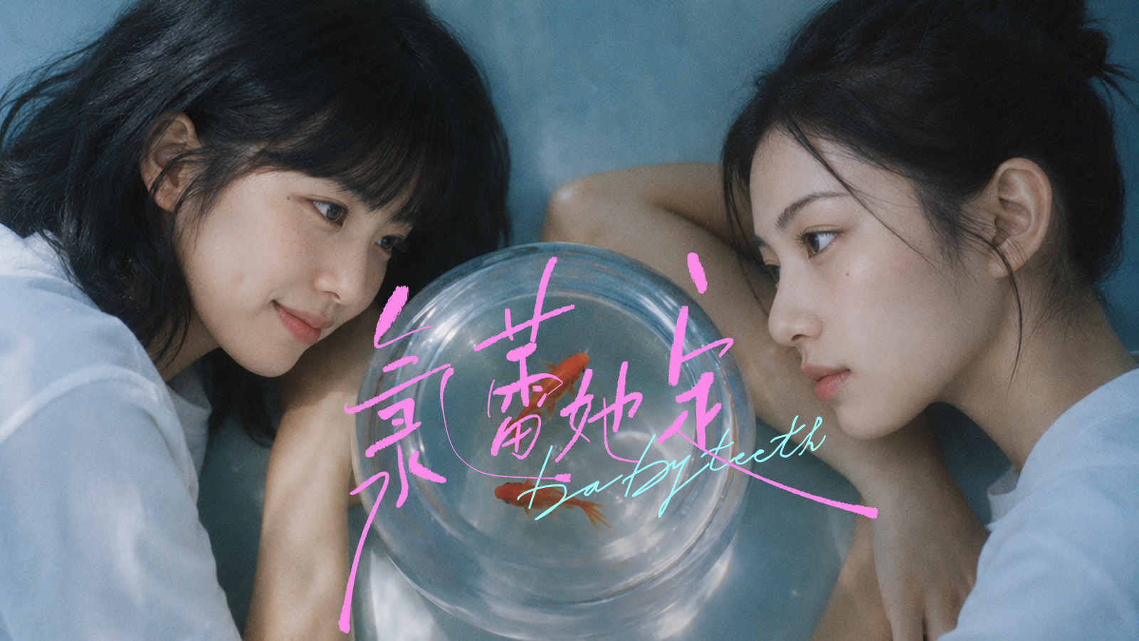 Two women facing one another across a glass fishbowl.