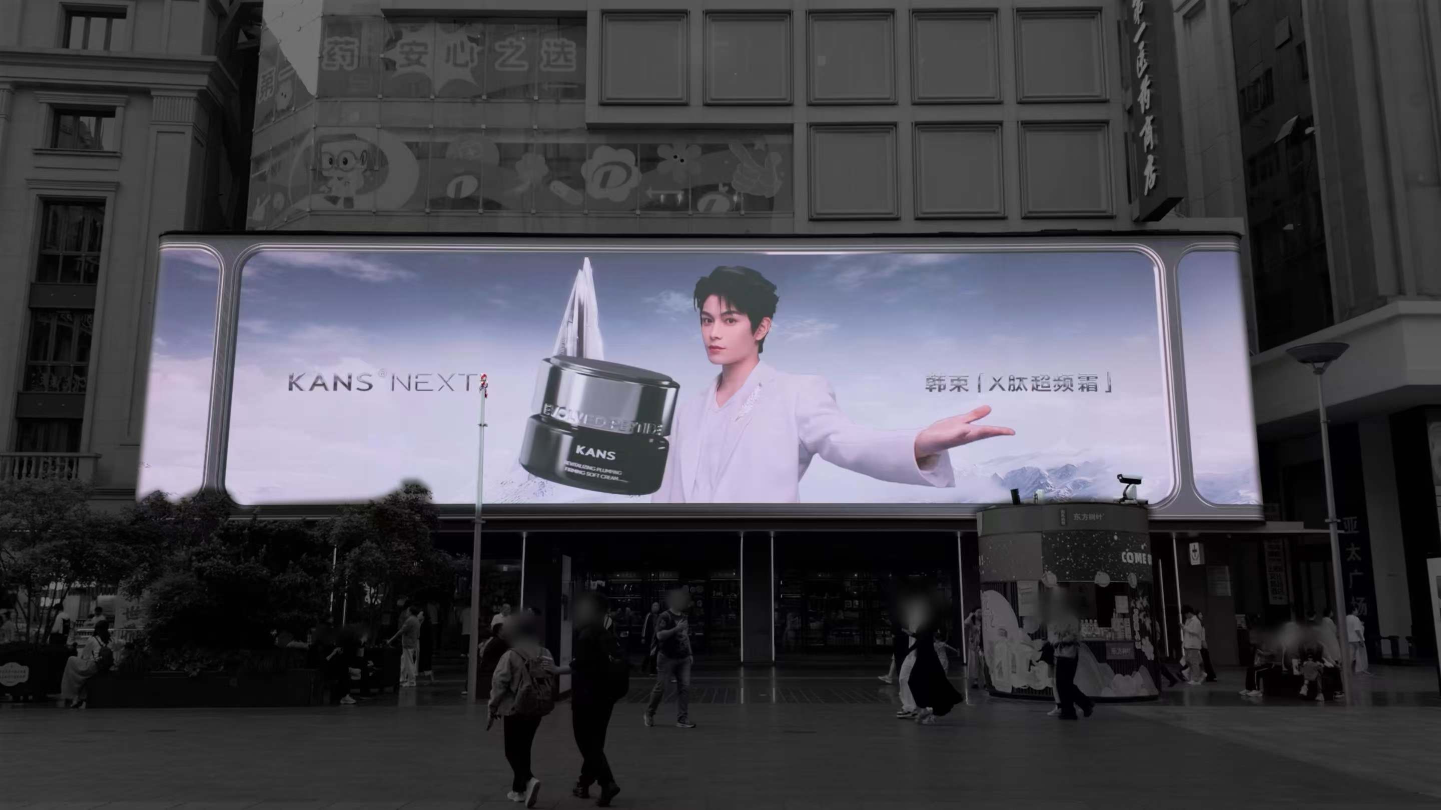 A KANS × Ding Yuxi 3D billboard displayed above a city street.